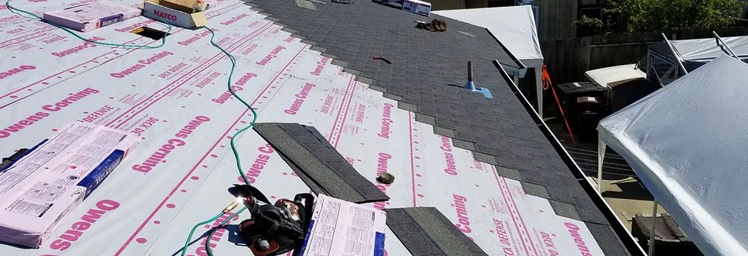 Fresh synthetic underlayment running across a full roof plane before the new roofing goes on