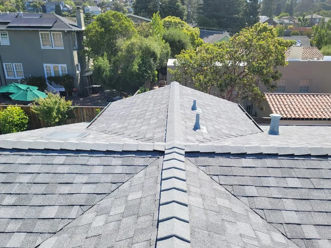 Finished hip roof with new architectural shingles surrounded by mature trees